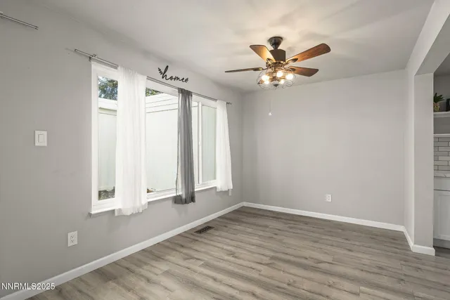 a view of an empty room with window and wooden floor