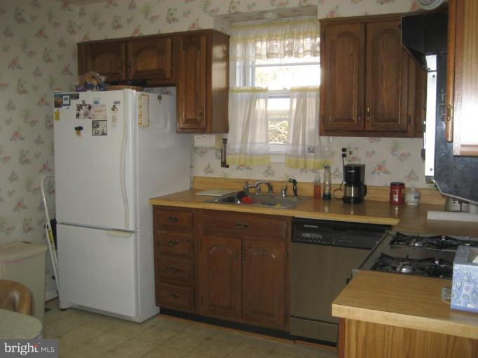 8710 Edmonston Road Berwyn Heights, MD 20740 - Photo 12 of 13 a kitchen with stainless steel appliances a refrigerator a sink a stove a microwave a sink and cabinets
