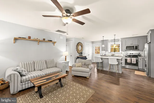 a living room with furniture kitchen view and a chandelier