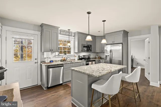 a kitchen with stainless steel appliances granite countertop a stove a sink dishwasher a refrigerator with a dining table and chairs