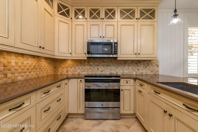 a view of an empty room with window and chandelier fan