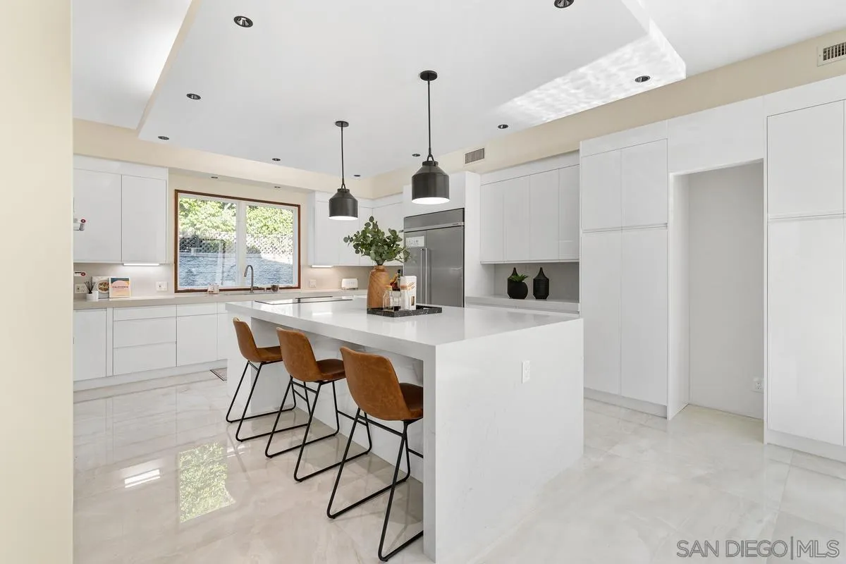 7911 El Paseo Grande La Jolla, CA 92037 - Photo 25 of 32 a kitchen with kitchen island a dining table chairs a sink and a window