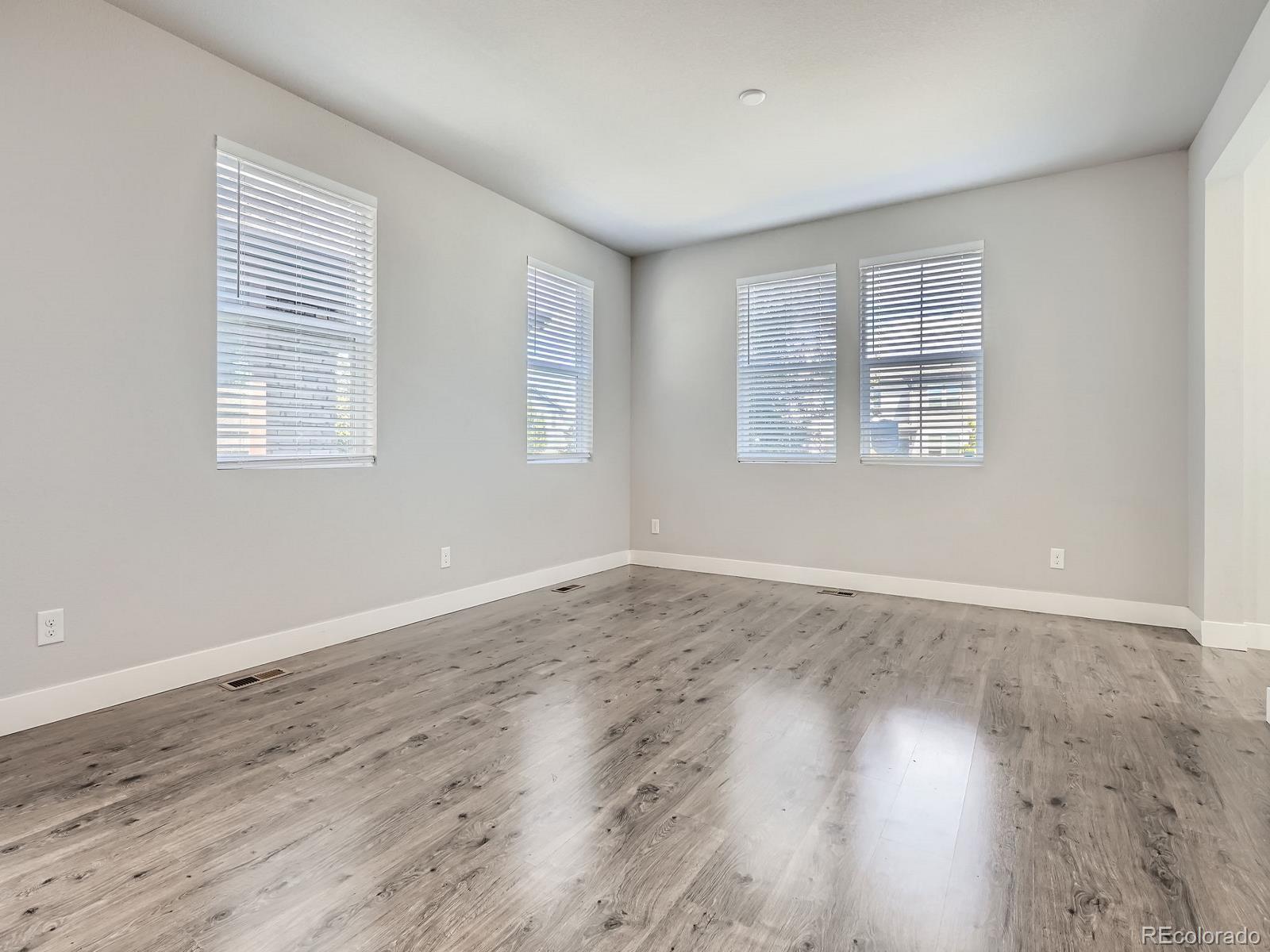 4773 Kittredge Street Denver, CO 80239 - Photo 3 of 32 a view of an empty room with wooden floor and a window