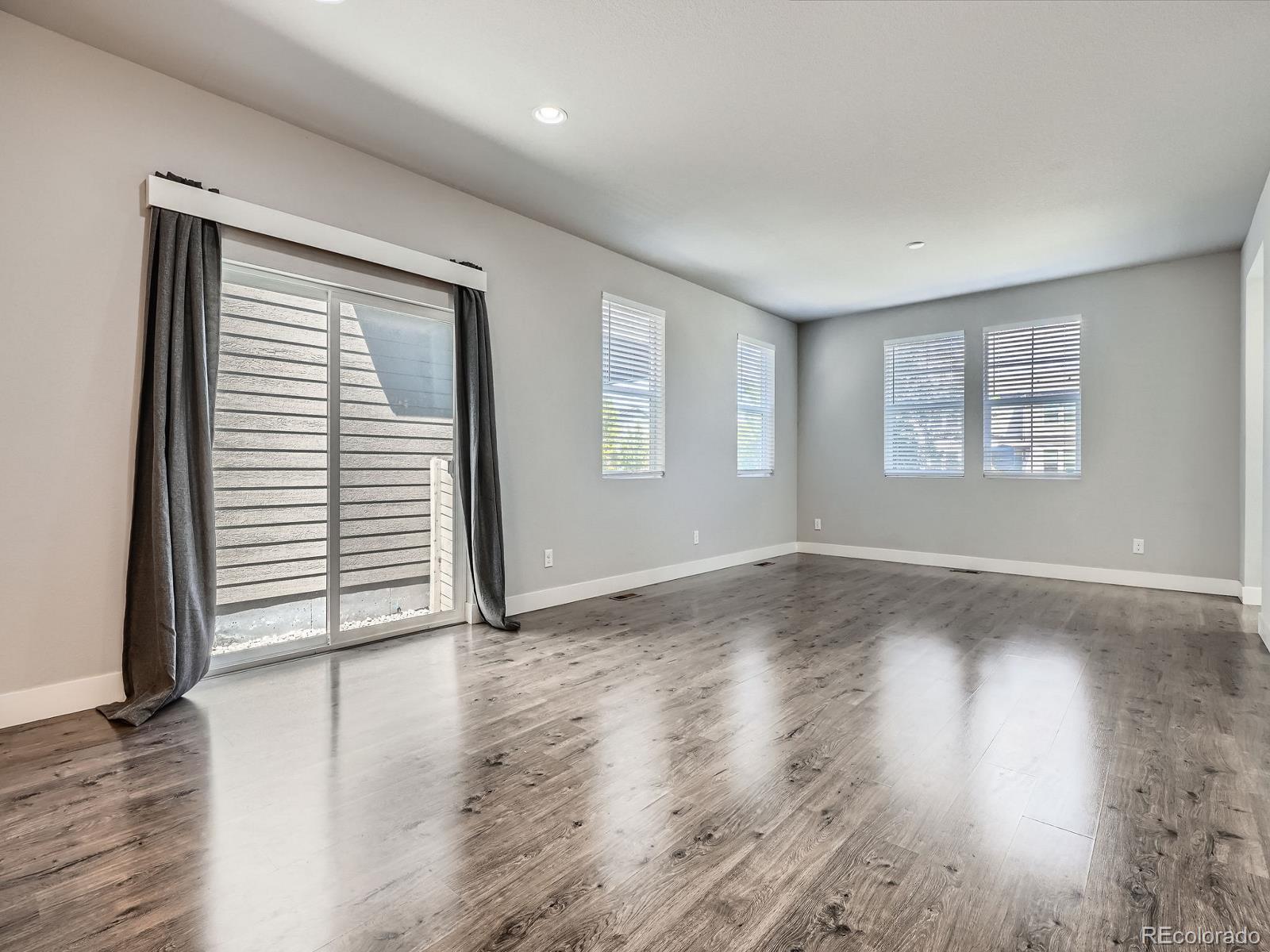 4773 Kittredge Street Denver, CO 80239 - Photo 6 of 32 an empty room with wooden floor and windows