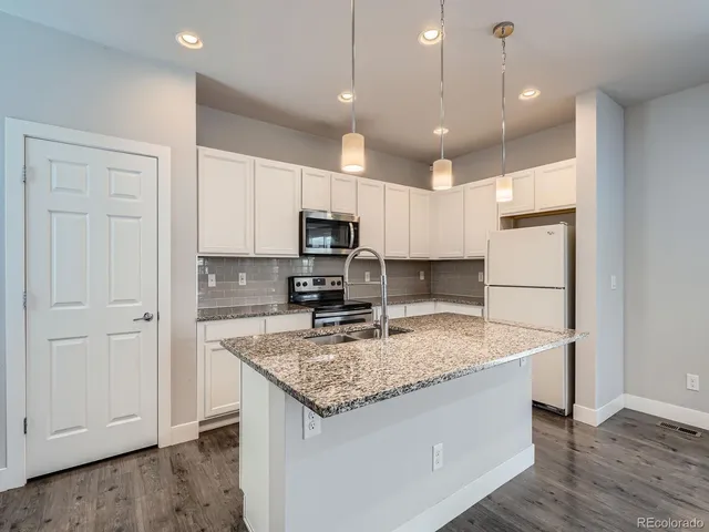 a kitchen that has a lot of cabinets and wooden floor
