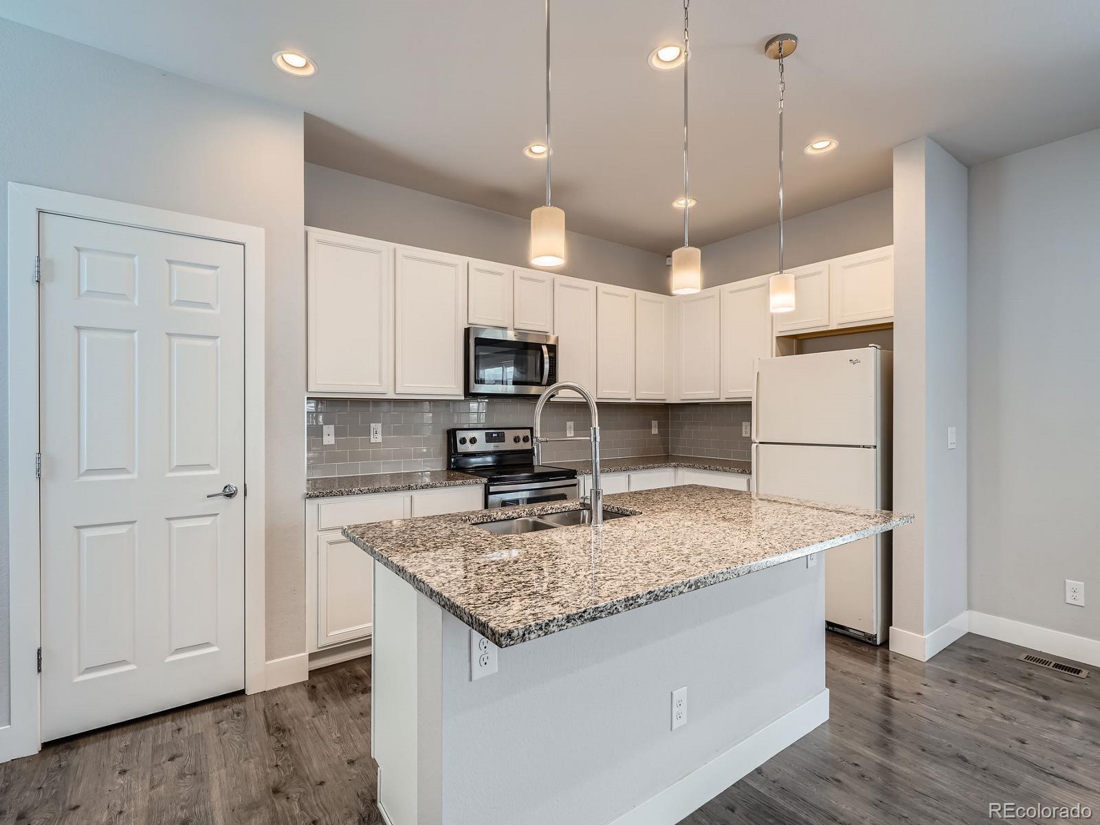 4773 Kittredge Street Denver, CO 80239 - Photo 8 of 32 a kitchen that has a lot of cabinets and wooden floor
