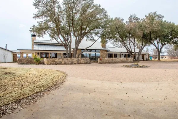 a view of large space with a tree in front of house