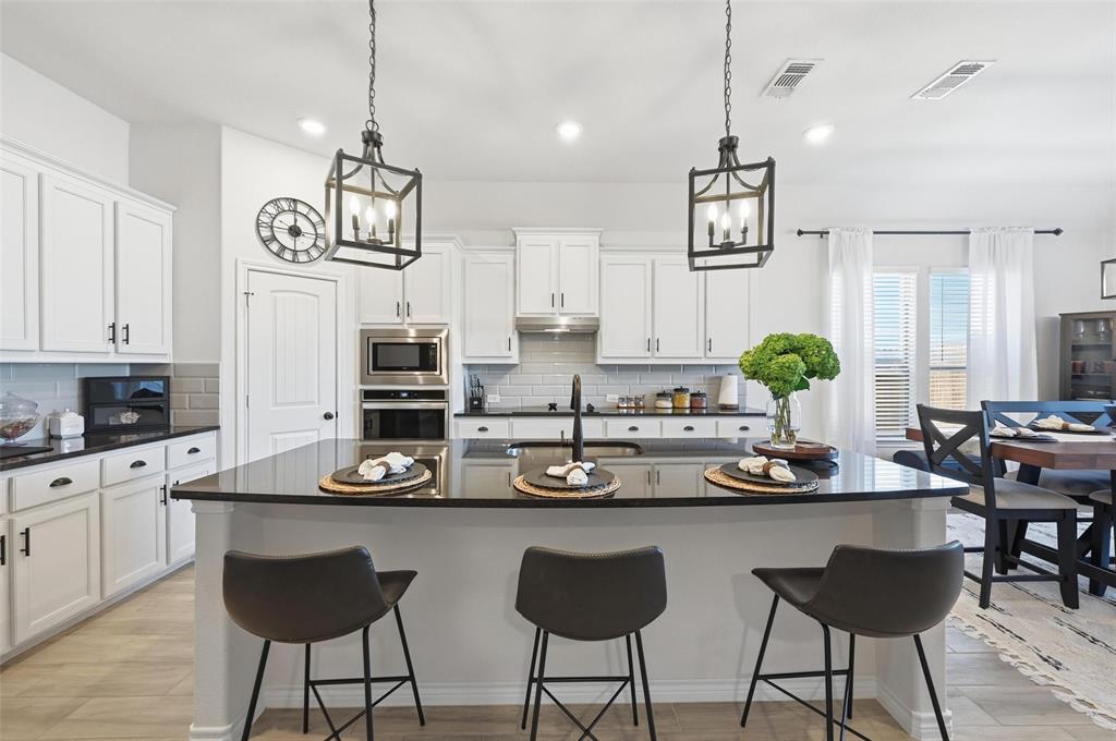 4425 Dandelion Lane Midlothian, TX 76065 - Photo 12 of 40 a kitchen with stainless steel appliances kitchen island granite countertop a table and chairs in it