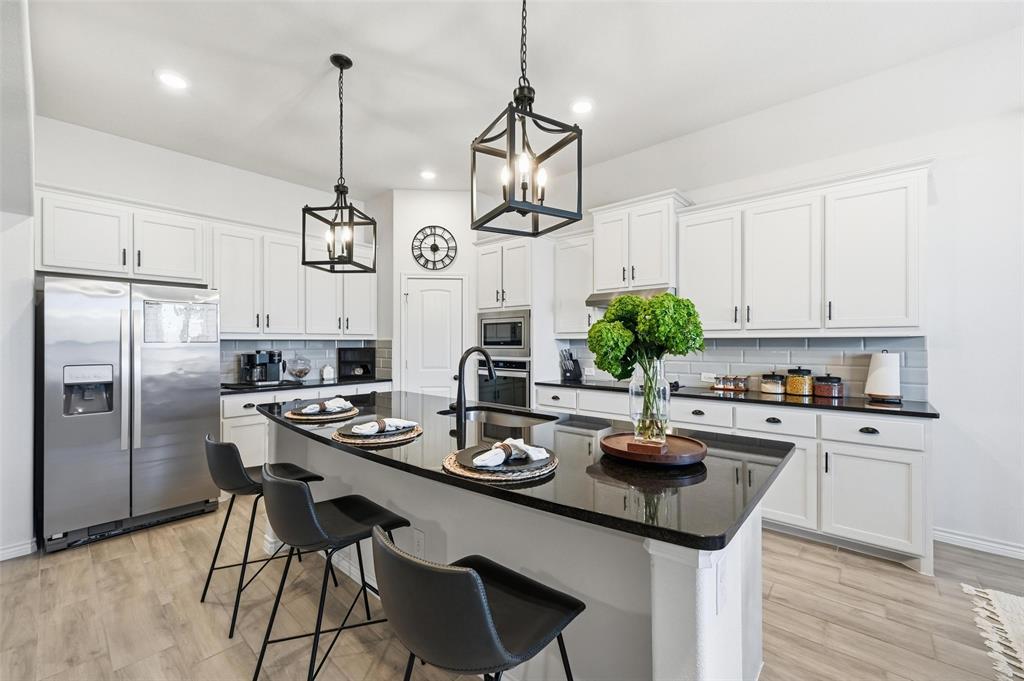 4425 Dandelion Lane Midlothian, TX 76065 - Photo 13 of 40 a kitchen with stainless steel appliances granite countertop a sink a stove a refrigerator and island with wooden floor