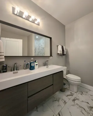 a bathroom with a toilet sink double vanity and mirror