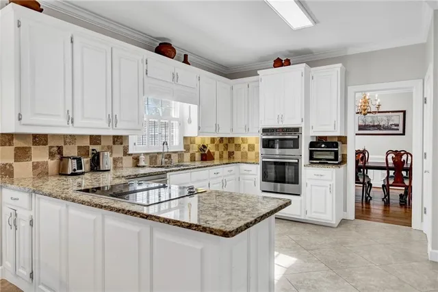 a large white kitchen with cabinets a sink and a stove