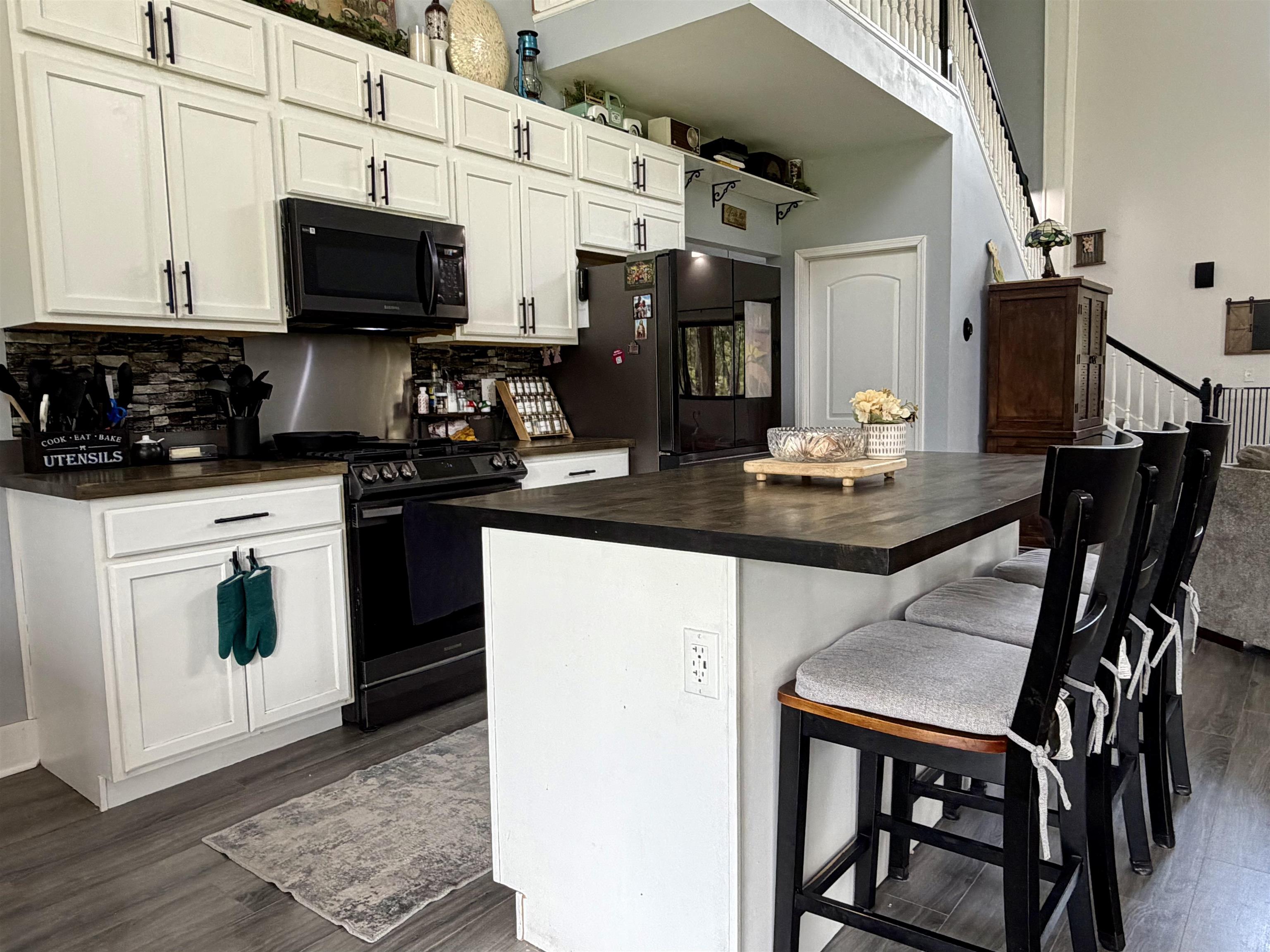 3670 Peavine Road Middleton, TN 38052 - Photo 11 of 36 Open-concept kitchen featuring white shaker-style cabinetry, dark countertops, and a stone-tile backsplash