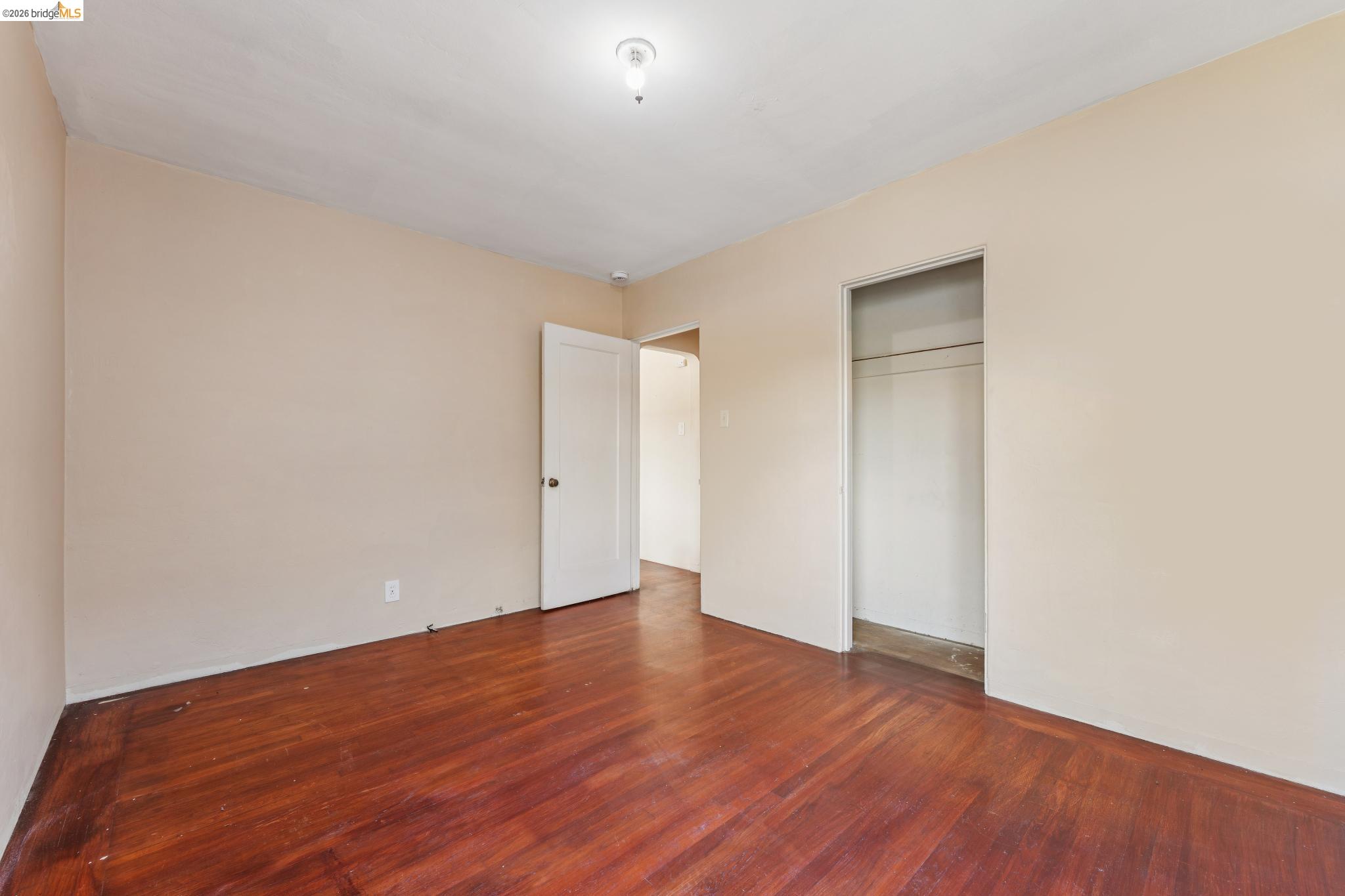 2879 Rheem Avenue Richmond, CA 94804 - Photo 29 of 45 Interior room featuring wood-finish flooring, light-colored walls, a ceiling-mounted light fixture, an open doorway, and an open closet with a hanging rod