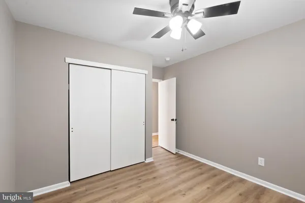 an empty room with wooden floor fan and windows