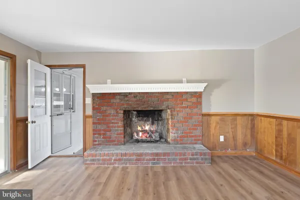a view of an empty room with wooden floor fireplace and a window