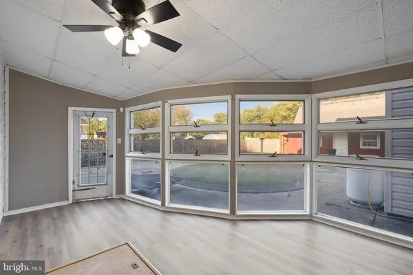 a view of an empty room with a window and kitchen view