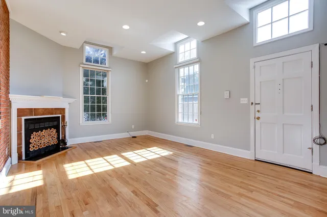 a view of an empty room with wooden floor fireplace and a window