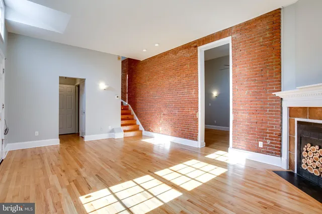 a view of an empty room with wooden floor and a fireplace