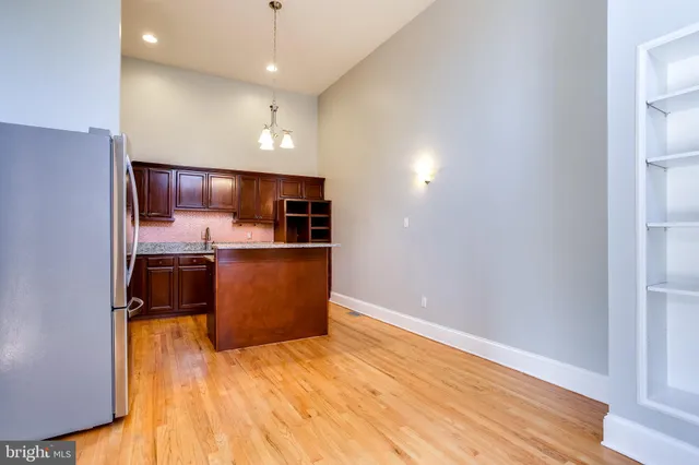 a kitchen with stainless steel appliances granite countertop a refrigerator a sink a stove and wooden floor