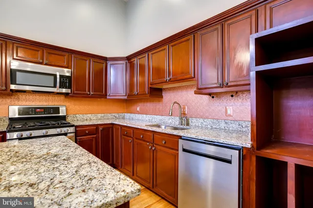 a kitchen with stainless steel appliances granite countertop wooden cabinets a stove top oven a sink and dishwasher