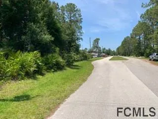 a view of a street with a house in the background