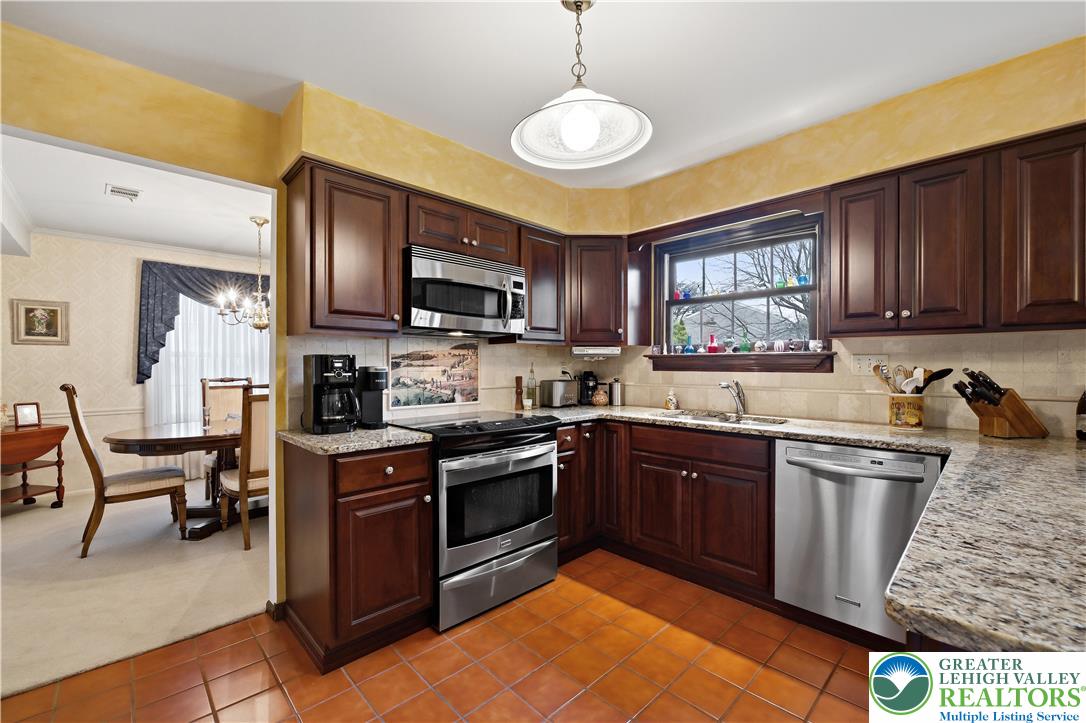 1700 Brandywine Road Allentown, PA 18104 - Photo 14 of 48 a kitchen with stainless steel appliances granite countertop a stove top oven a sink dishwasher a dining table and chairs with wooden floor