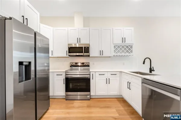 a kitchen with stainless steel appliances a refrigerator sink and white cabinets