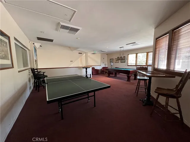 a room with furniture pool table gym equipment wooden floor and windows