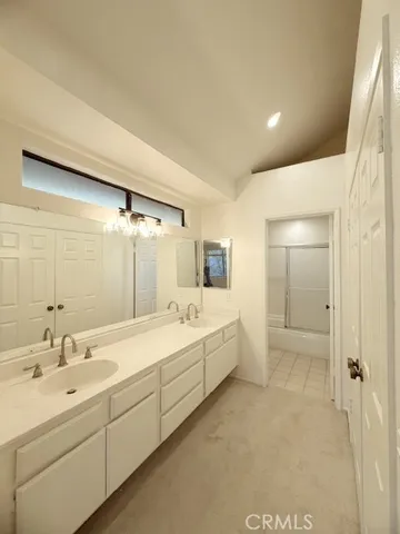 a bathroom with a double vanity sink a mirror and a bathtub