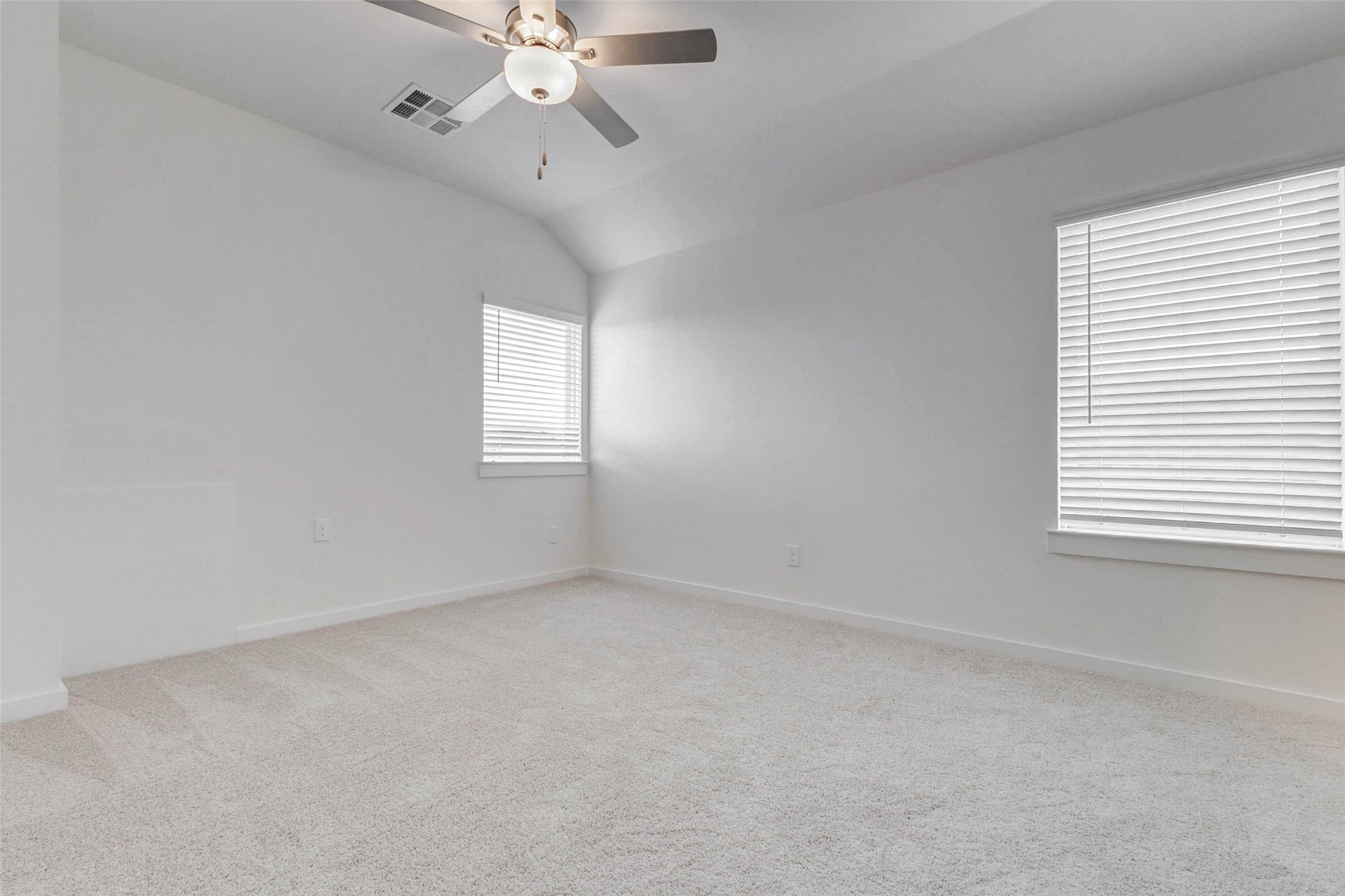 6471 Escondido Drive Rosharon, TX 77583 - Photo 26 of 33 Bright secondary bedroom featuring soft carpet, neutral paint, ceiling fan, and two windows with blinds for natural light. The vaulted ceiling adds a sense of openness, while the simple, fresh finishes make the room easy to furnish as a bedroom, study, or flex space.