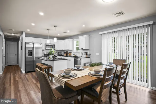 a kitchen with a dining table chairs and refrigerator
