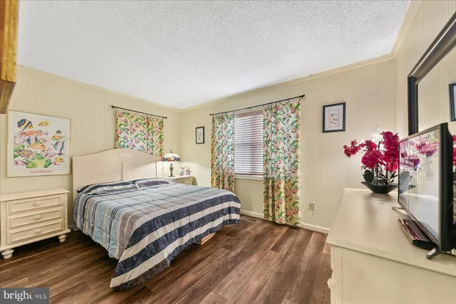 a bedroom with a bed potted plant on dresser and a window