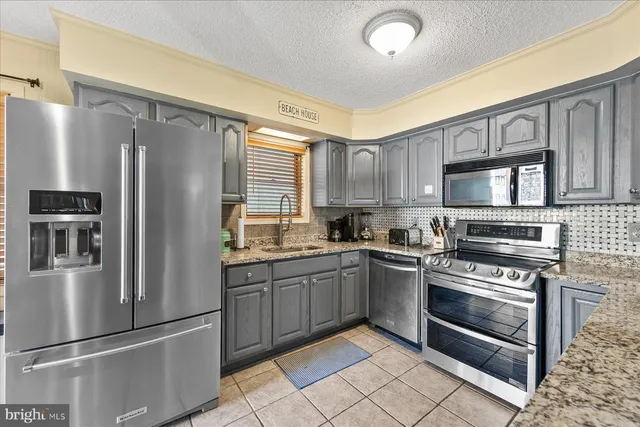 a kitchen with stainless steel appliances granite countertop a refrigerator stove and sink