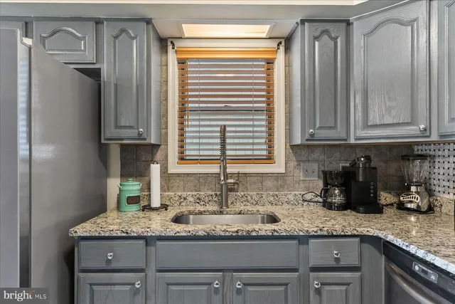a kitchen with granite countertop a sink stainless steel appliances white cabinets and a window