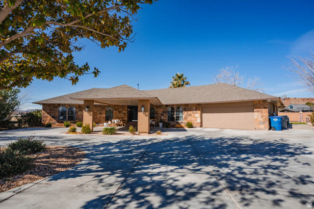 980 Cactus Circle St. George, UT 84790 - Photo 72 of 77 Ranch-style house featuring concrete driveway, an attached garage, covered porch, stone siding, and a shingled roof