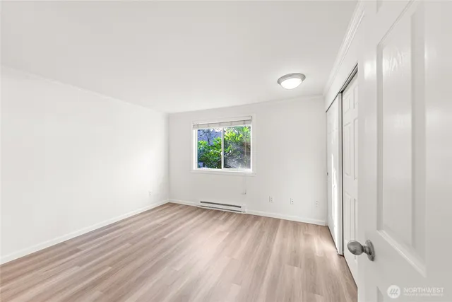 an empty room with wooden floor and windows