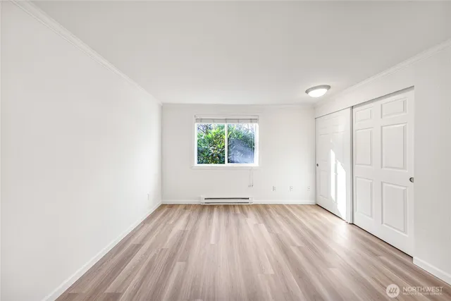 an empty room with wooden floor a ceiling fan and windows