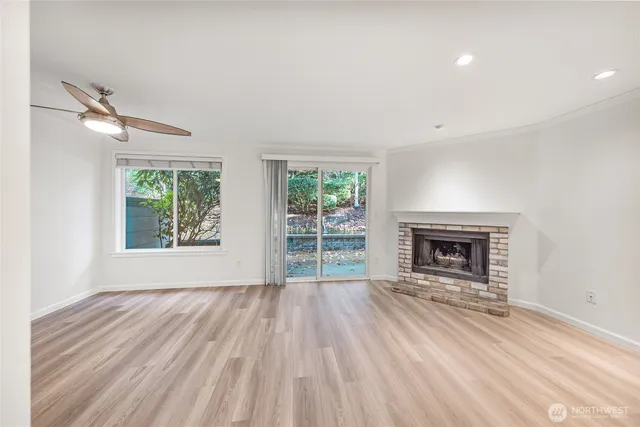 an empty room with windows a fireplace and wooden floor