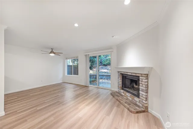 an empty room with wooden floor fireplace and windows