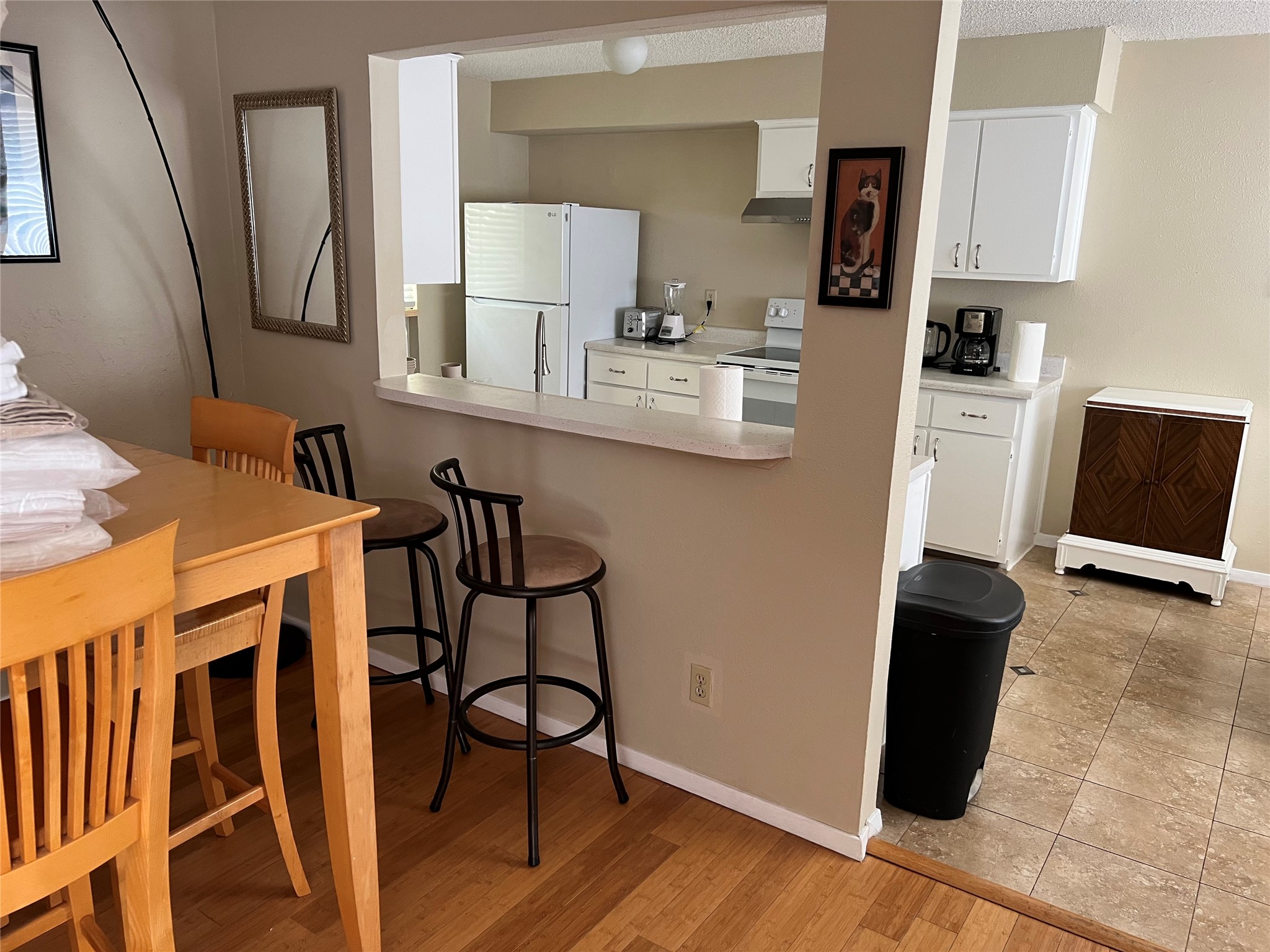 903 The High Road Austin, TX 78746 - Photo 17 of 37 a kitchen with stainless steel appliances a sink a stove a microwave a dining table and chairs with wooden floor