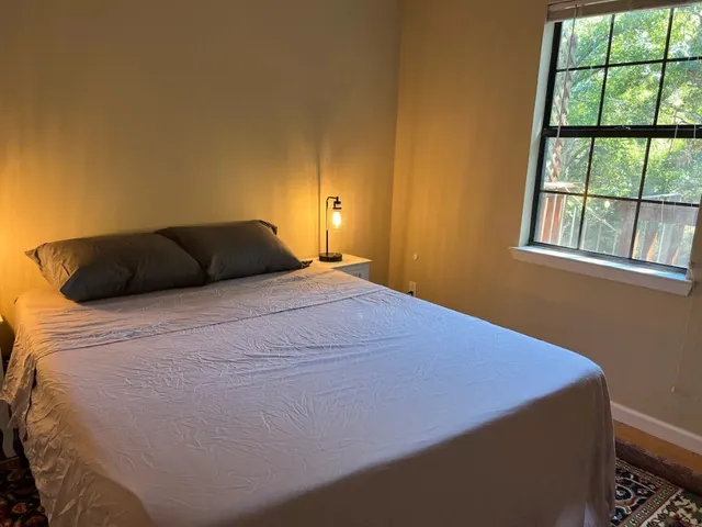 a bedroom with a bed window and lamp