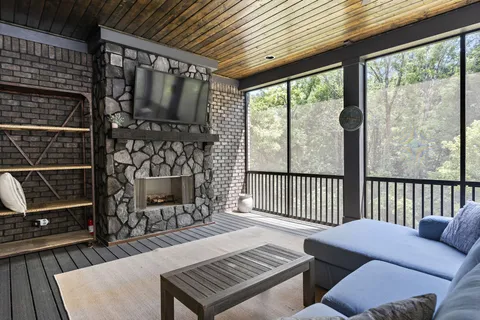 a living room with furniture a flat screen tv and a floor to ceiling window