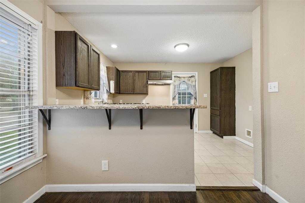 117 Moon Street Cleburne, TX 76033 - Photo 12 of 28 a kitchen with kitchen island granite countertop a stove top oven a sink and a refrigerator