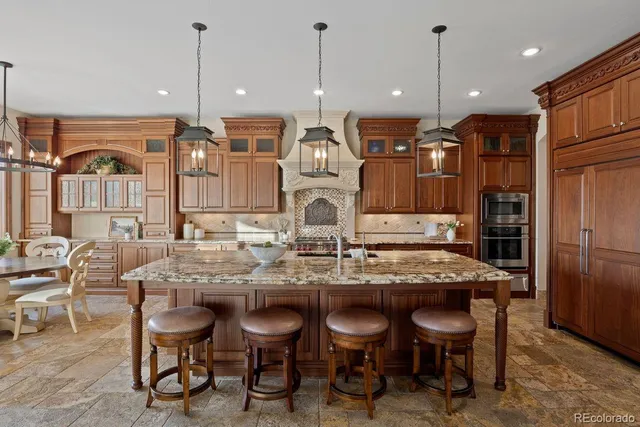 a kitchen with kitchen island granite countertop a table chairs sink and cabinets