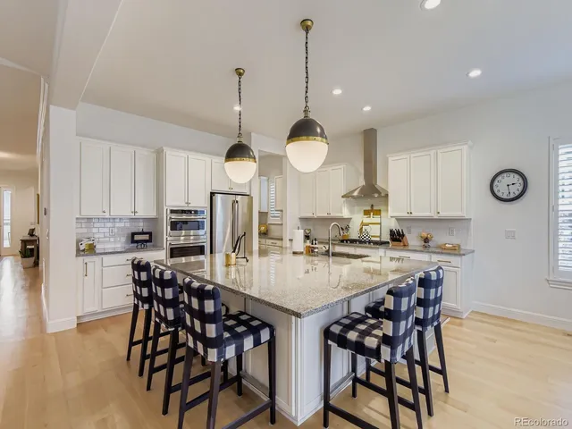 a kitchen with stainless steel appliances a dining table chairs and stove top oven