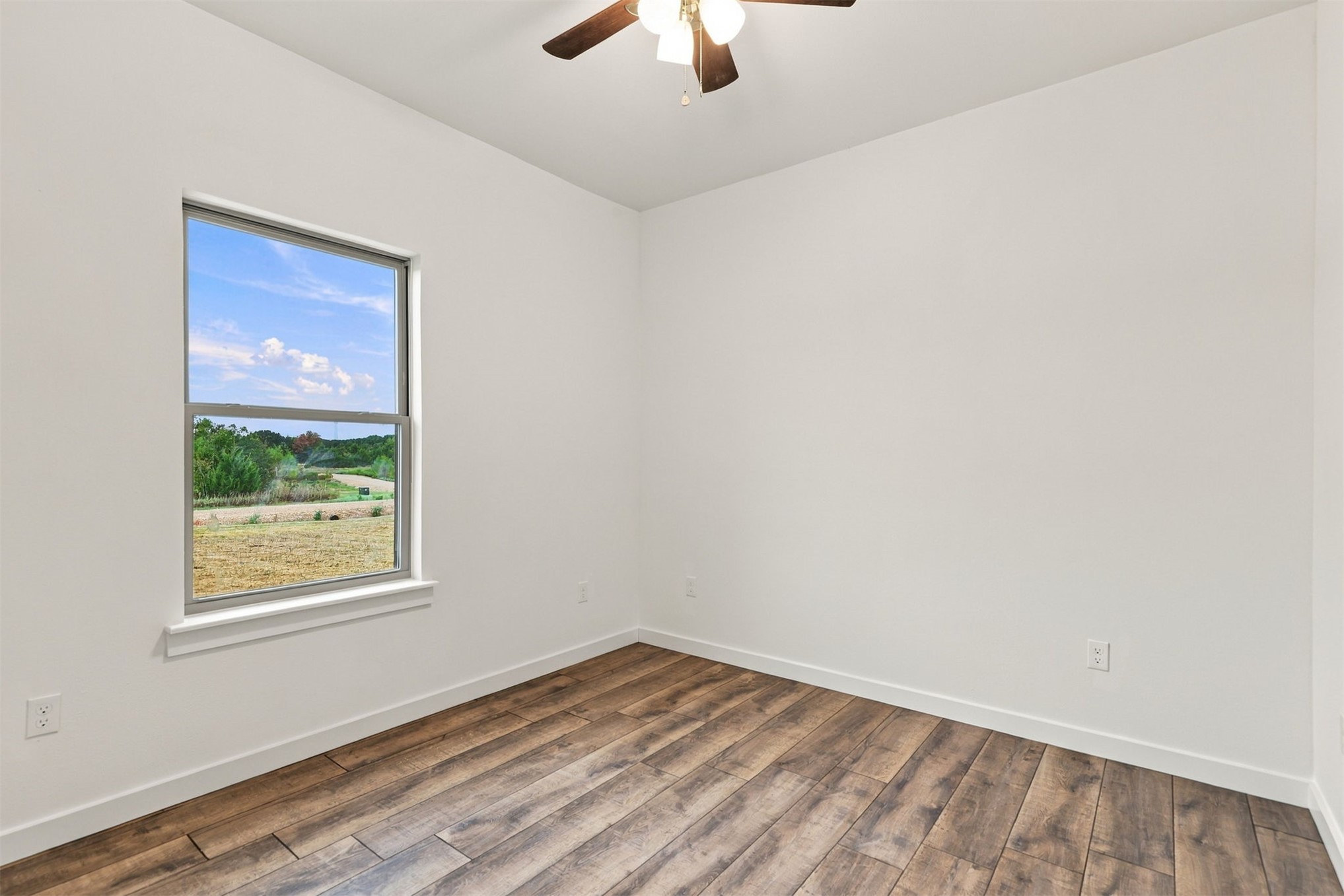 21 Redbird Lane Colbert, OK 74733 - Photo 9 of 27 Wood-finish flooring, white walls, and a window providing natural light