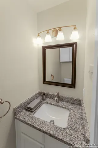 a bathroom with a granite countertop sink a mirror and vanity