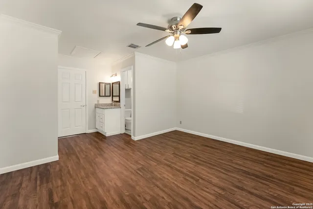 an empty room with wooden floor and stainless steel appliances