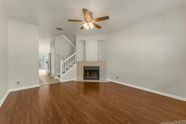 a view of an empty room with wooden floor and a fireplace