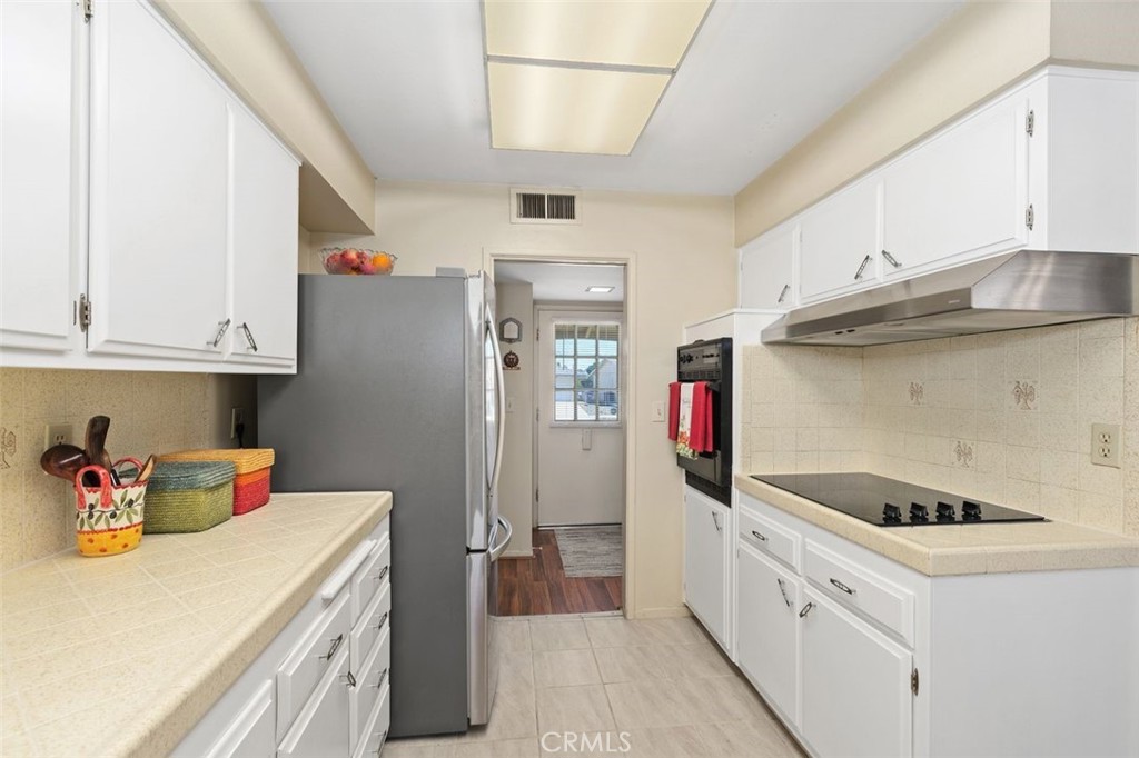 26480 Ridgemoor Road Menifee, CA 92586 - Photo 5 of 32 a kitchen with a refrigerator and white cabinets